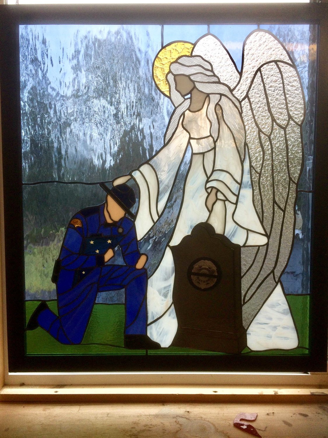 The window depicts a state trooper kneeling at a grave while being comforted by an angel. It aims to recognize those who have died during their service with the state patrol.